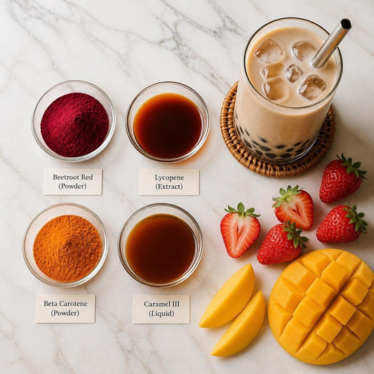 Four labelled dishes of food colours beside an iced milk tea with tapioca pearls, strawberries and mango
