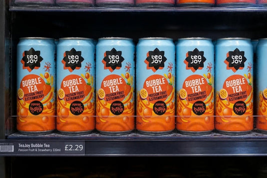 A row of TeaJoy Passion Fruit & Strawberry bubble tea cans on a chiller shelf